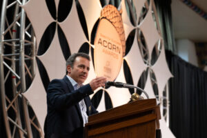 Dan DeLaurentis stands at a podium addressing the crowd.