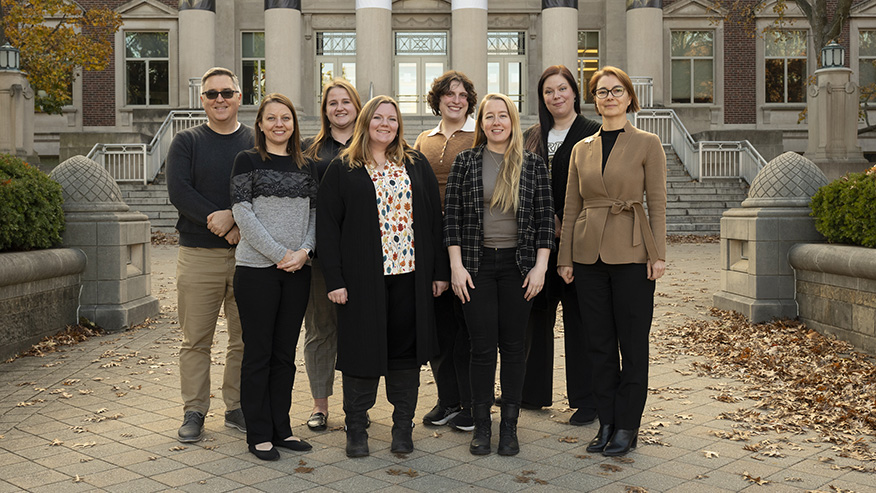 A group of people stand near the steps of Hovde Hall.