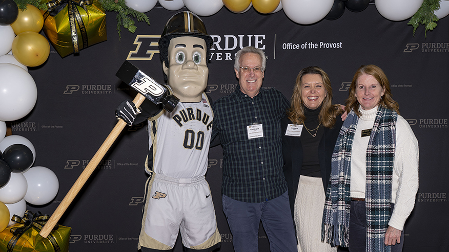 People stand with Purdue Pete in front of a Purdue banner