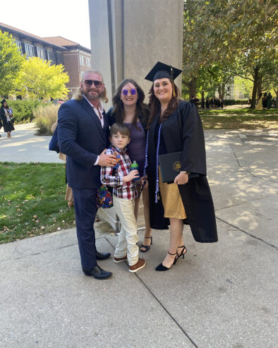 A graduate standing next to her family members outside