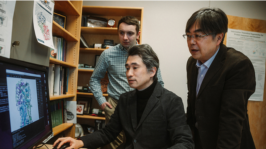 Charles Christoffer, Genki Terashi and Daisuke Kihara looking at a computer screen