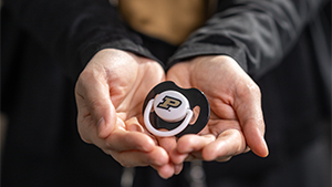 A Purdue University branded pacifier held in two open hands