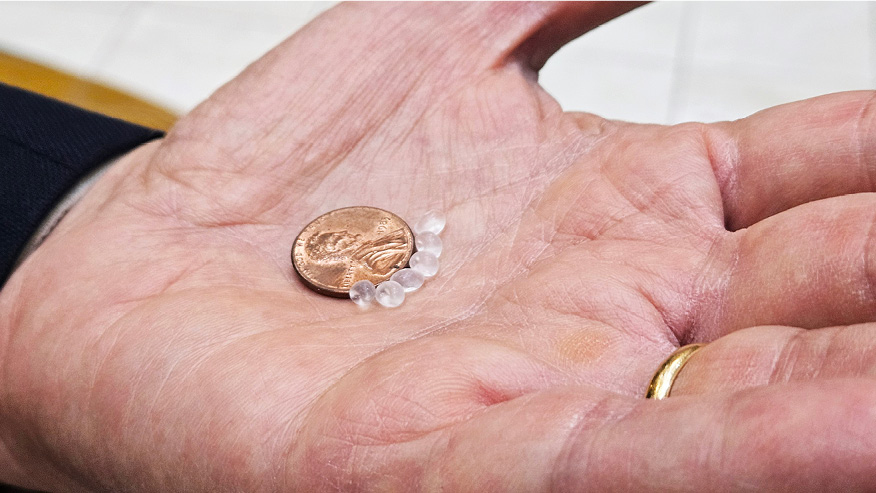 A penny and six opaque beads smaller than the penny sit in Rusi Taleyarkhan’s hand.