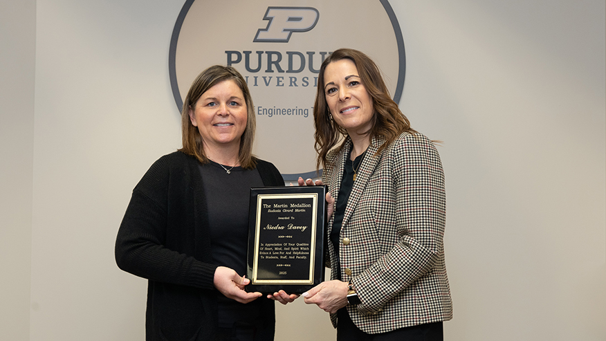 Niedra Davey and Amy Boyle stand together holding a plaque.
