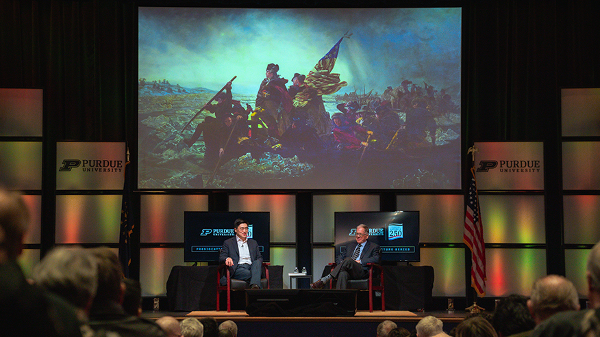 Two men sitting together on stage