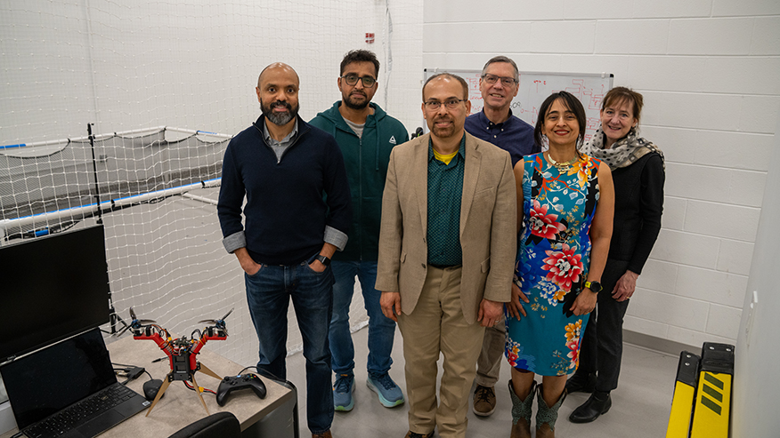 Group standing next to model