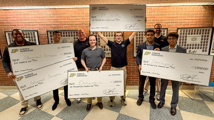 Purdue University students hold oversized checks, and three Purdue Innovates Incubator leaders stand among them.