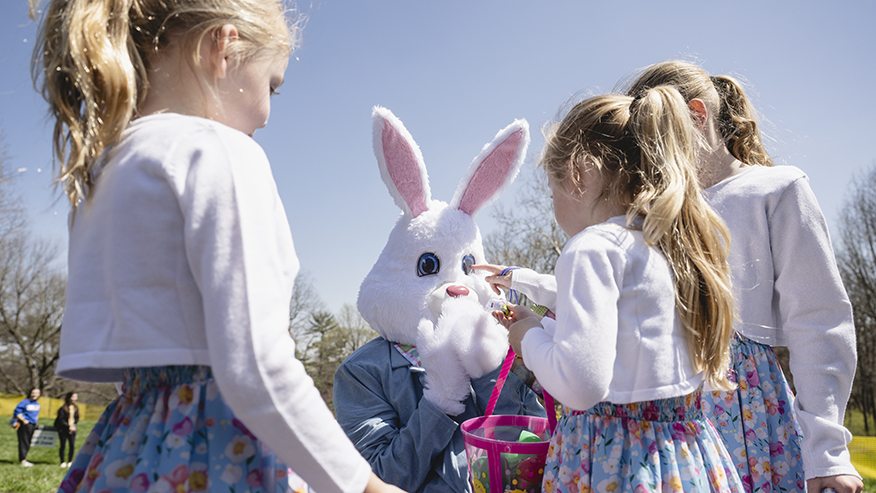 Three children interacting with the Easter bunny