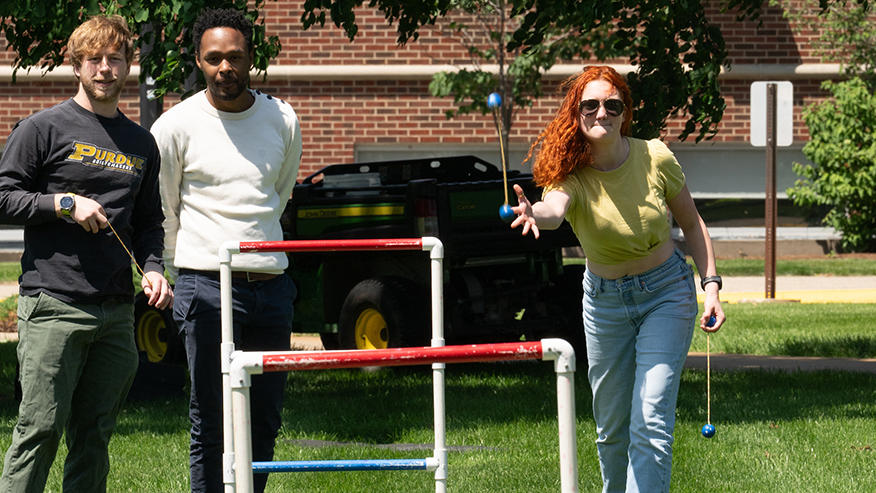 Three people playing ladder toss.