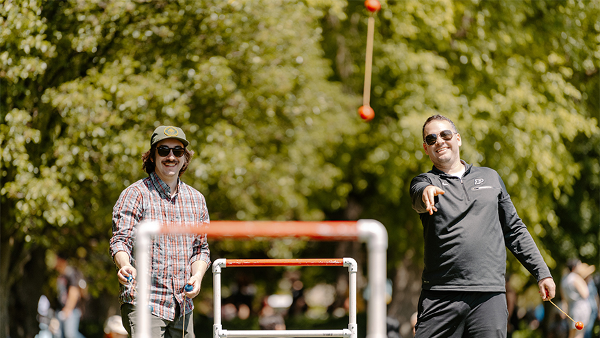 Two people play ladder toss outside.