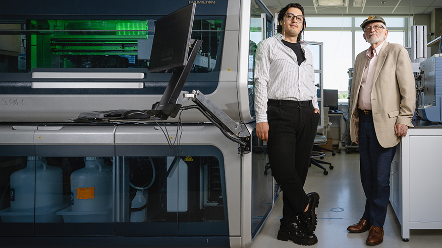Researchers stand with mass spectrometry platform in lab.