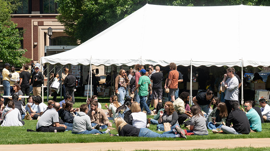 A crowd sits near a tent on Memorial Mall.
