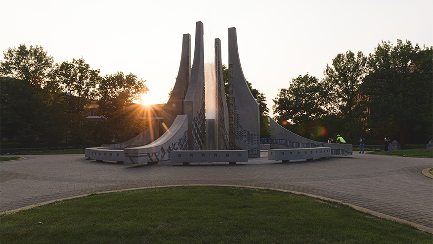Sun behind campus stone sculpture