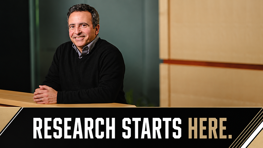 Dan DeLaurentis, Executive Vice President of Research, seated at a wooden desk in an office setting, with the text 'RESEARCH STARTS HERE.' displayed in a banner across the bottom of the image.