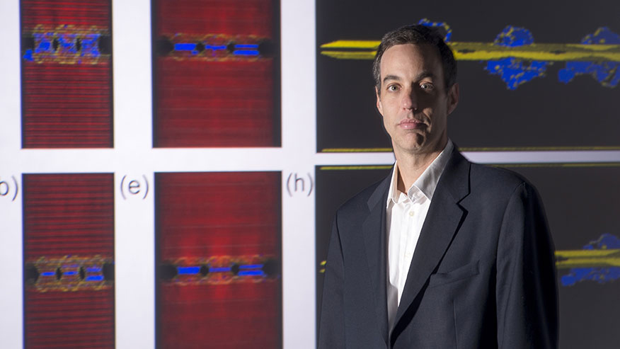 Alejandro Strachan stands in front of a research display.