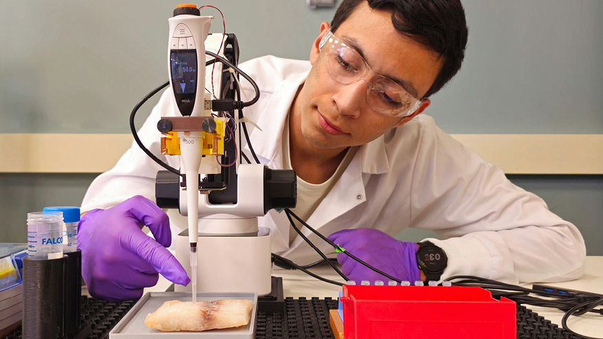 Jesus Ladino works with a device whose pipette touches a food sample.