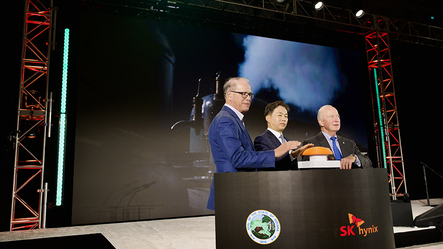 Mike Braun (left), Kwak Noh-Jung and Mitch Daniels stand poised to press a large orange button.