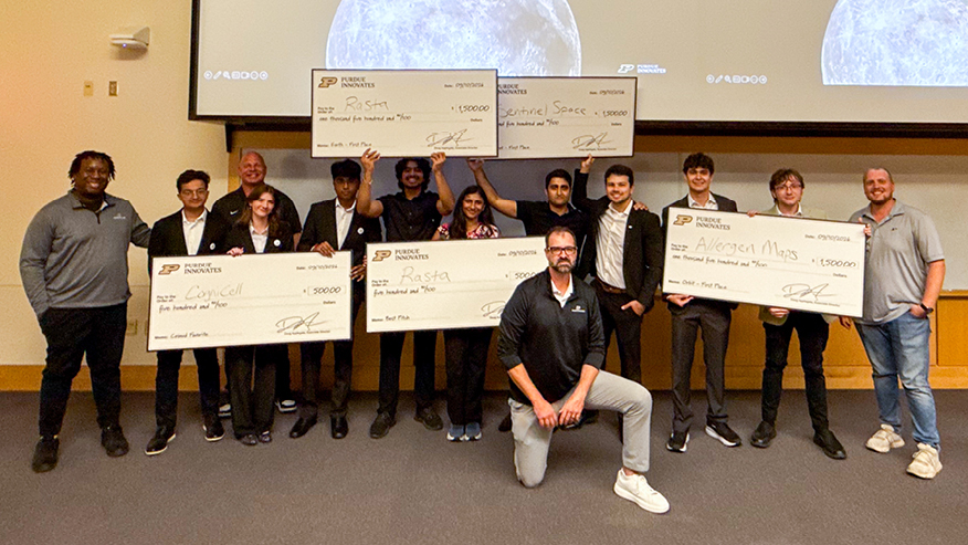 A group of students holds oversized checks and looks into the camera.