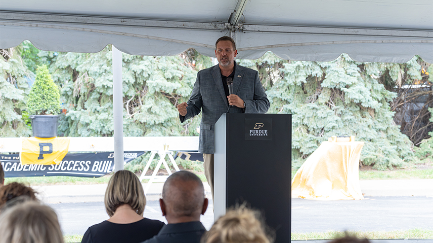 A Purdue leader speaks at a podium during the Academic Success Building topping-out ceremony in Indianapolis.