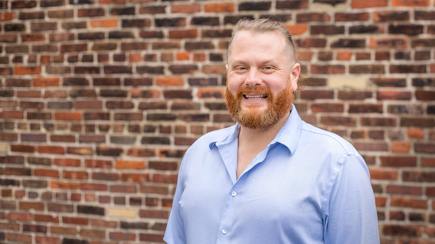 Man smiling in front of brick wall