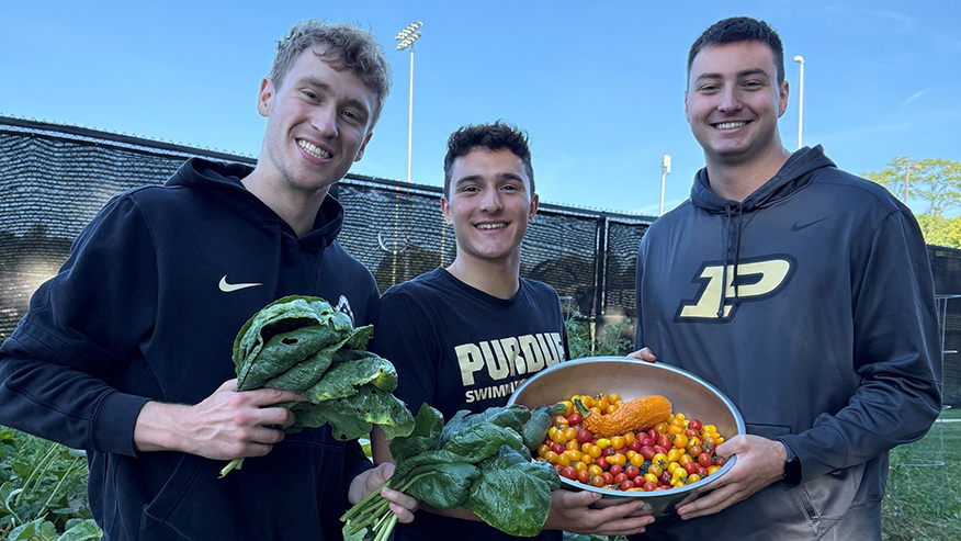 3 students showing off produce grown in garden