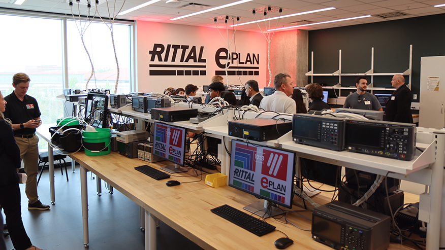 People talking in a lab with Rittal and Eplan branding.