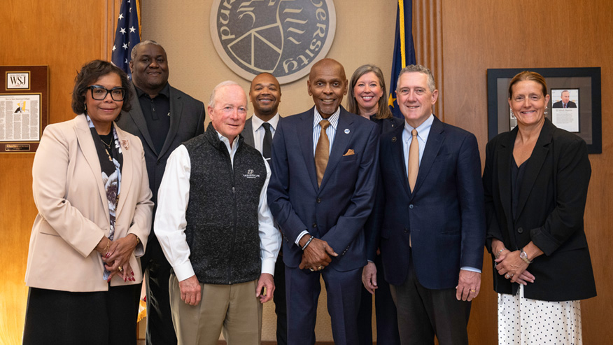 Purdue interim President Mitch Daniels, donor Roland G. Parrish and others pose in front of the Purdue University seal.