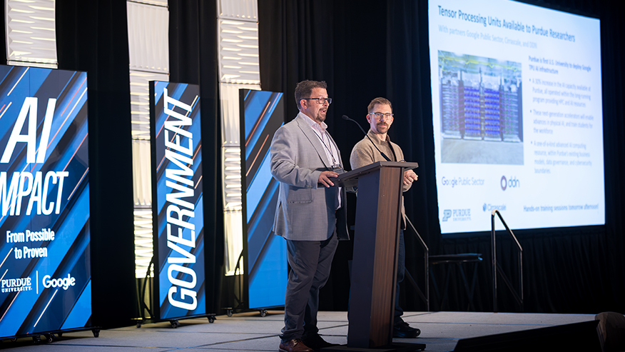 Two speakers at a podium announce new Google AI computing resources for Purdue researchers at the AI Impact summit.