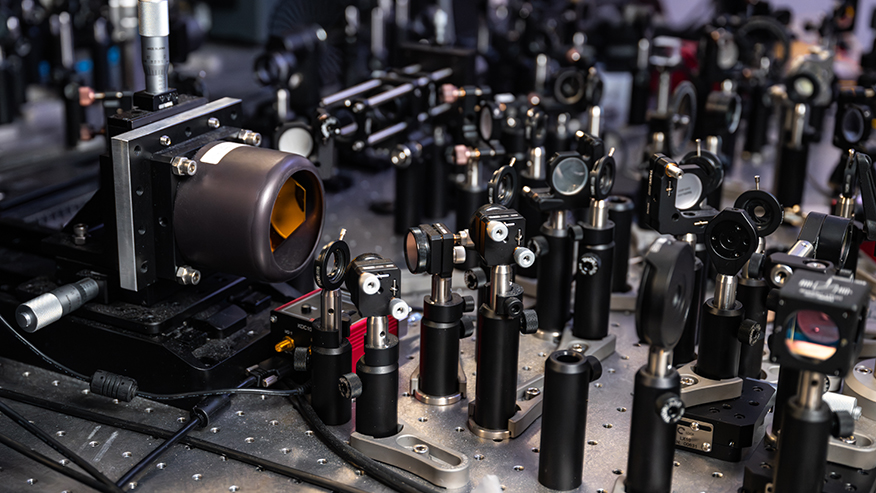 Lenses, mirrors and lasers crowd a custom-built microscopy apparatus in the lab of researcher Libai Huang.