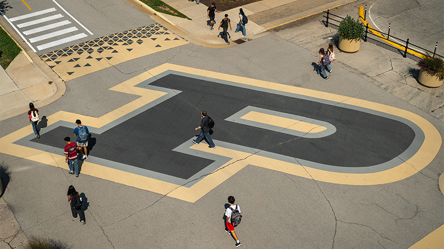 Students cross a large, painted letter 