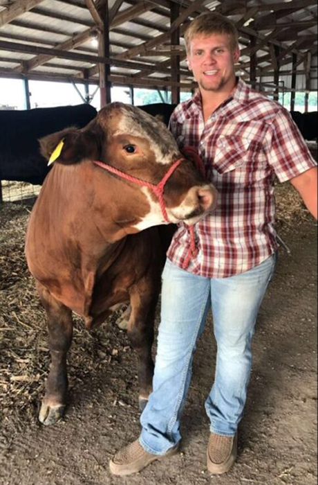 farmers stands next to cow