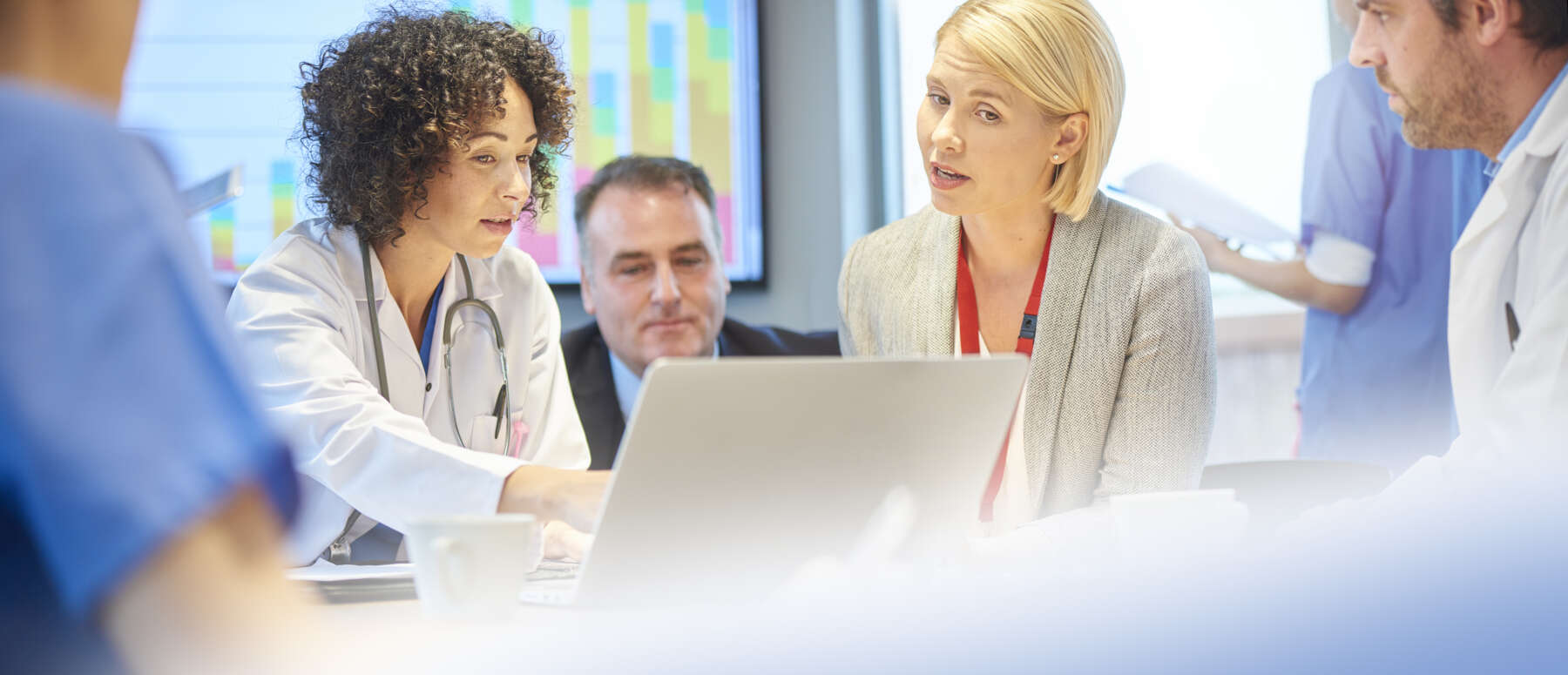 a mixed group of healthcare professional and business people meet around a conference table .