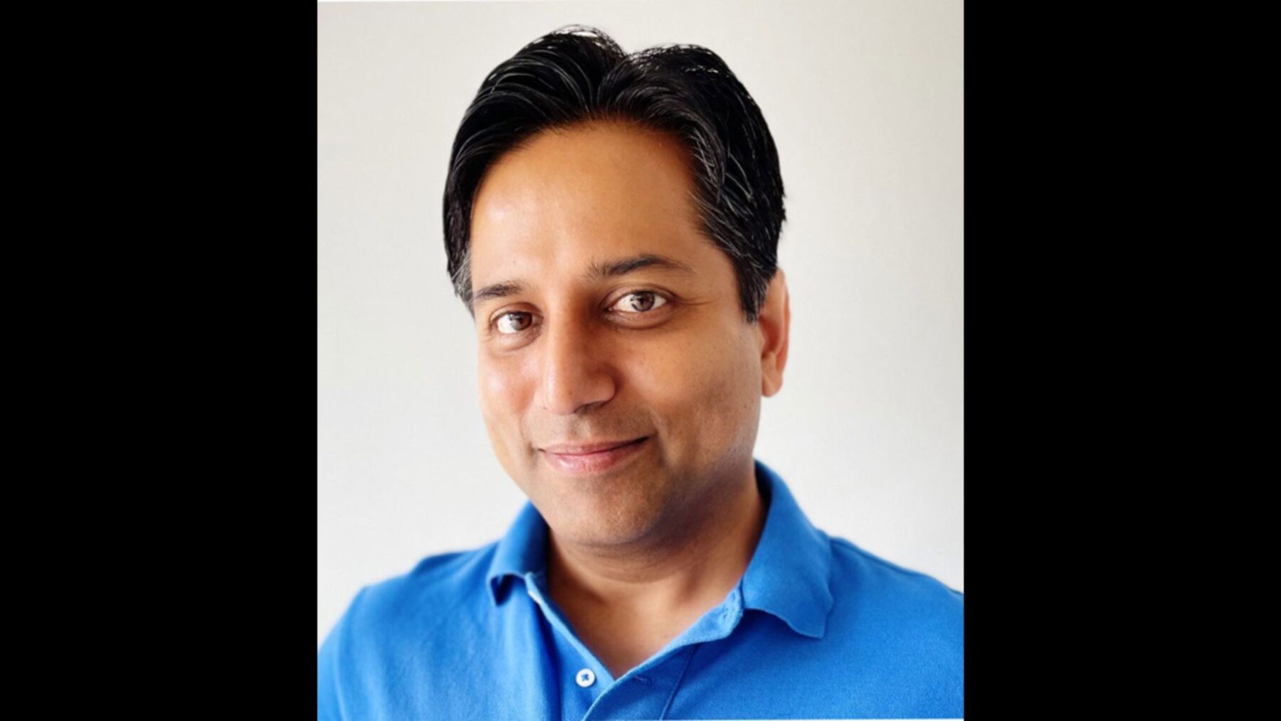 Mehul Patel looks at the camera wearing a blue, button-up shirt.