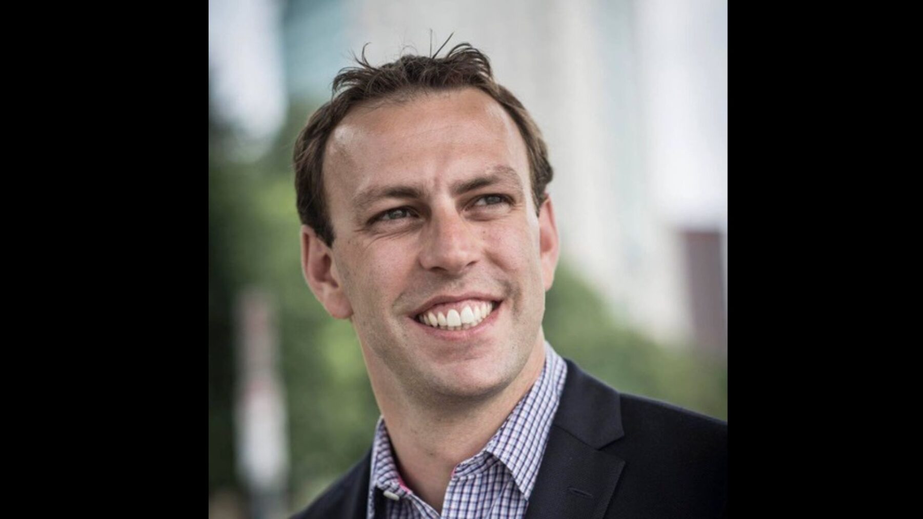 Andrew Walz looking directly into the camera in front of a neutral background.