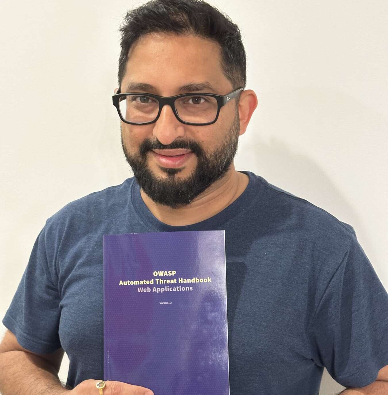 Areejit Banerjee holding his policy brief. He is wearing a blue shirt and black glasses,