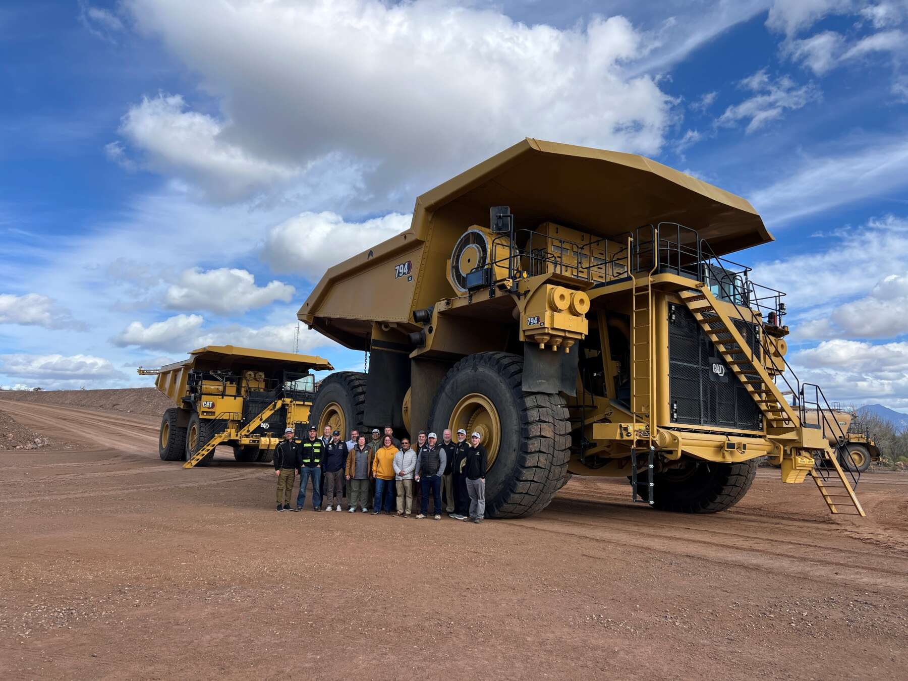 A group of Purdue representatives stand in front of a large Caterpillar truck in the Arizona desert.