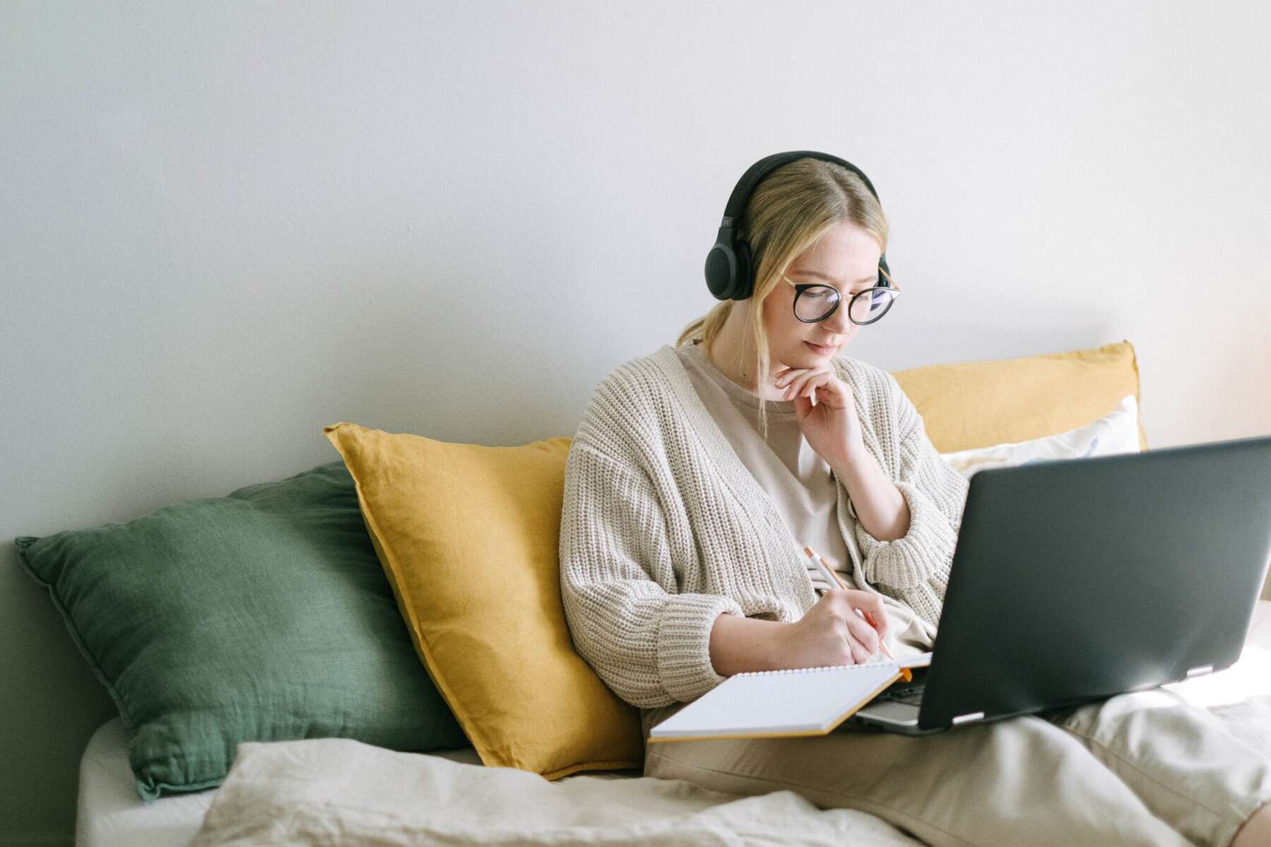 A student studies on her laptop in bed.