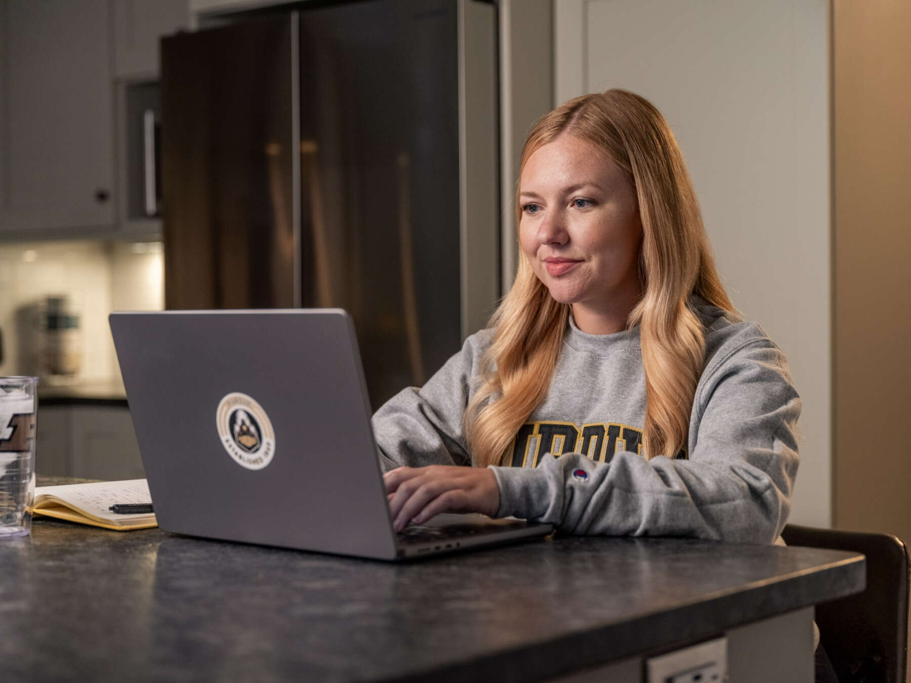 A woman sits in front of a laptop and works. She is wearing a 