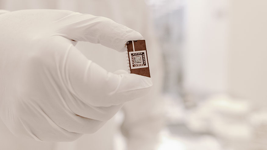 A picture of a scientist holding a microchip wearing white gloves