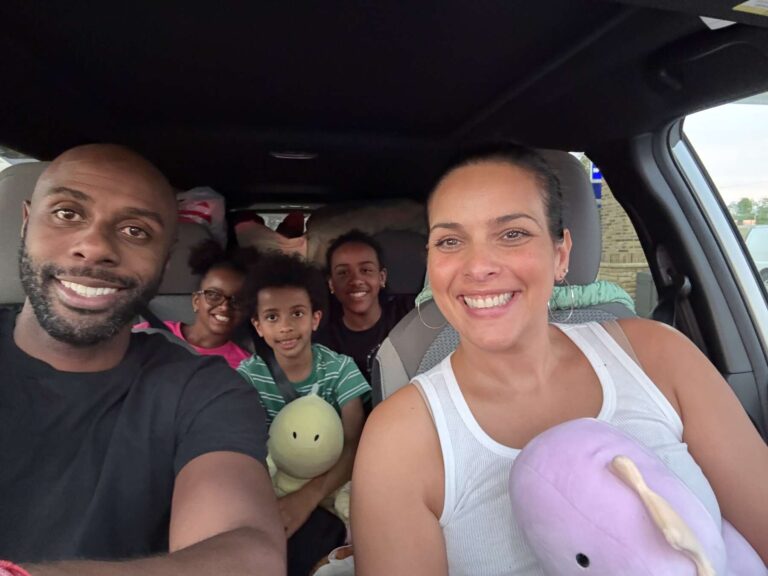 Tamara Grant and her family smile for a photo in a car. They are wearing casual clothing.