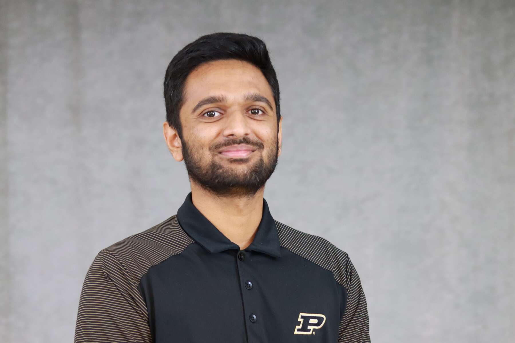 Paul Thomas posing for a headshot. He is wearing a black and grey Purdue pullover.