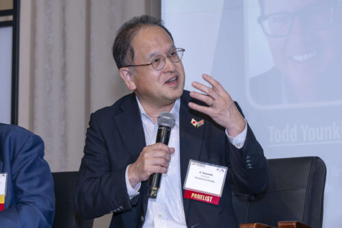 Akinobu Teramoto, director of the Research Institute for Semiconductor Engineering at Hiroshima University. Akinobu Teramoto addresses a crowd at Purdue University. He is holding a microphone and wearing a black blazer and striped dress shirt.