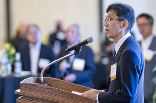 Shuji Kakegawa, managing officer and director of the Institute of Technology, Shimizu Corporation. Shuji Kakegawa addresses a crowd at Purdue University. He is wearing a black blazer, white dress shirt and navy blue tie.
