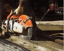 A worker wet-cutting concrete to reduce silica dust presence.