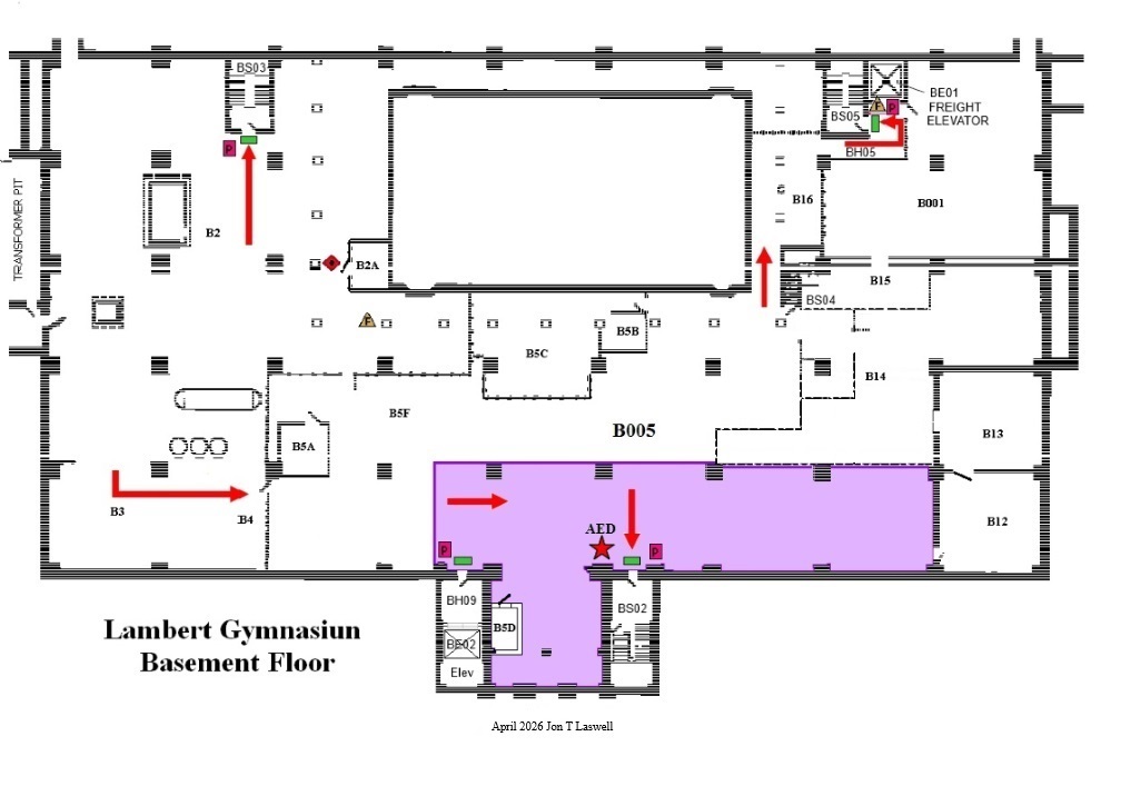 A detailed black-and-white floor plan labeled at the bottom “LAMB Gymnasium Basement Floor.” The diagram shows a large rectangular central space surrounded by smaller rooms labeled B01 through B16. Corridors run around the perimeter and between rooms. A long highlighted purple area spans the lower-right portion of the basement, connected to a smaller purple section at the bottom center indicates Severe Weather Safe Zones. Red arrows directional routes through hallways and rooms, including arrows pointing right, upward, and downward within the purple-highlighted area indicate Evacuation Paths. A red star labeled “AED” marks the location of an automated external defibrillator near the middle of the purple zone. Stairwells are labeled BS01, BS02, BS03, BS04, and BS05. An elevator is labeled “Freight Elevator” near the upper-right corner. The drawing includes door symbols, walls, and room boundaries typical of an architectural floor plan. A note at the bottom reads “April 2026 Jon T. Laswell.”