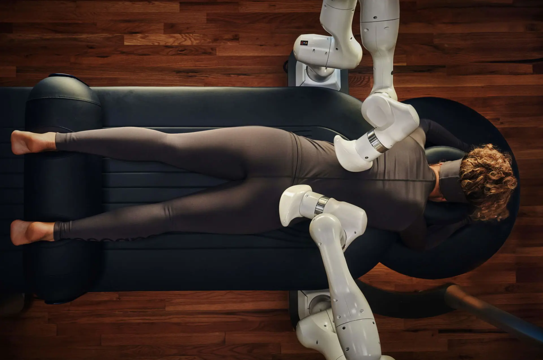 Looking down on women laying on Aescape AI-powered massage table