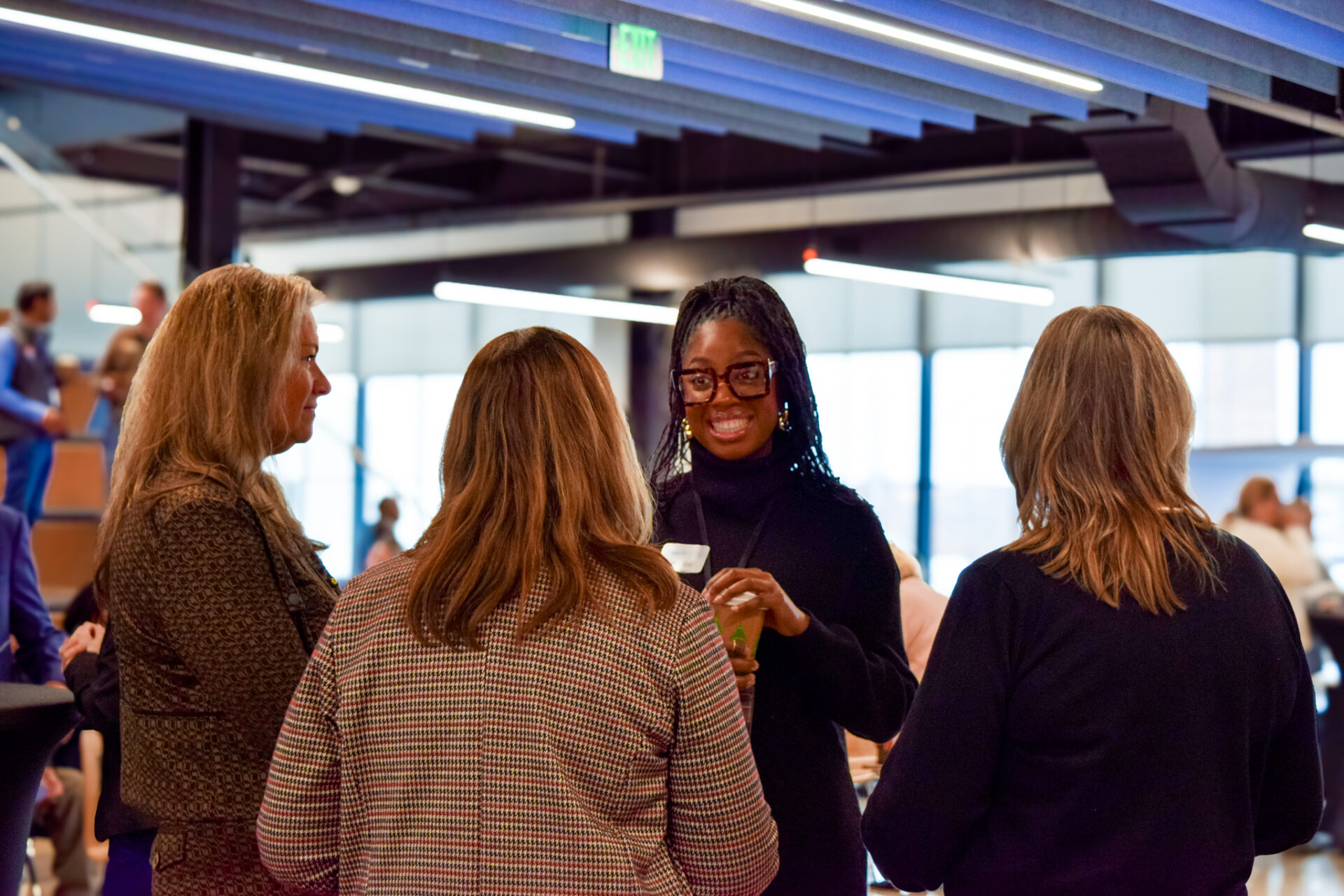Four women standing in a circle chatting at the Relationship to Partnership event.