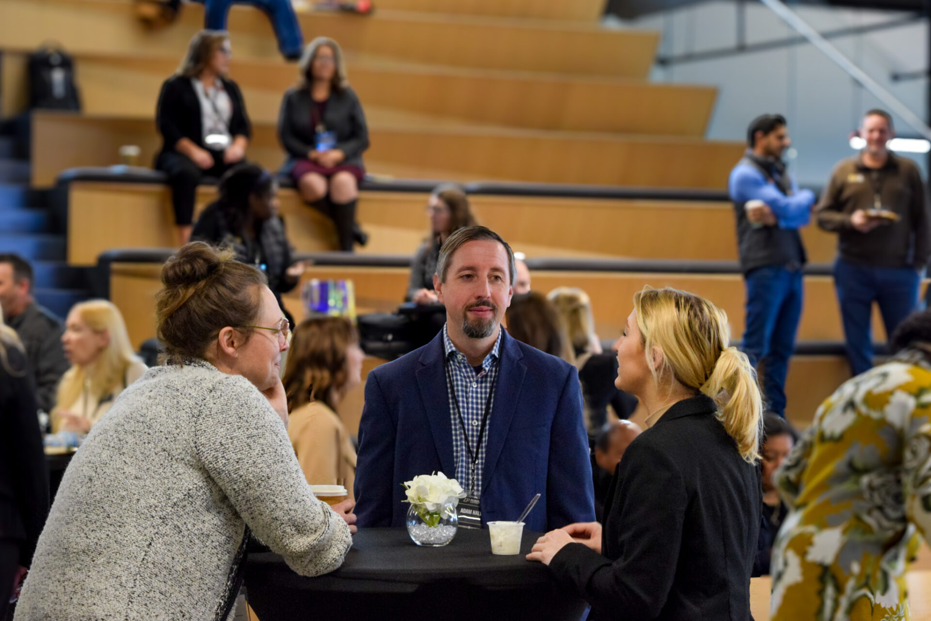 Two women and a man standing at a table each with a coffee cup, conversing at the R2P event.