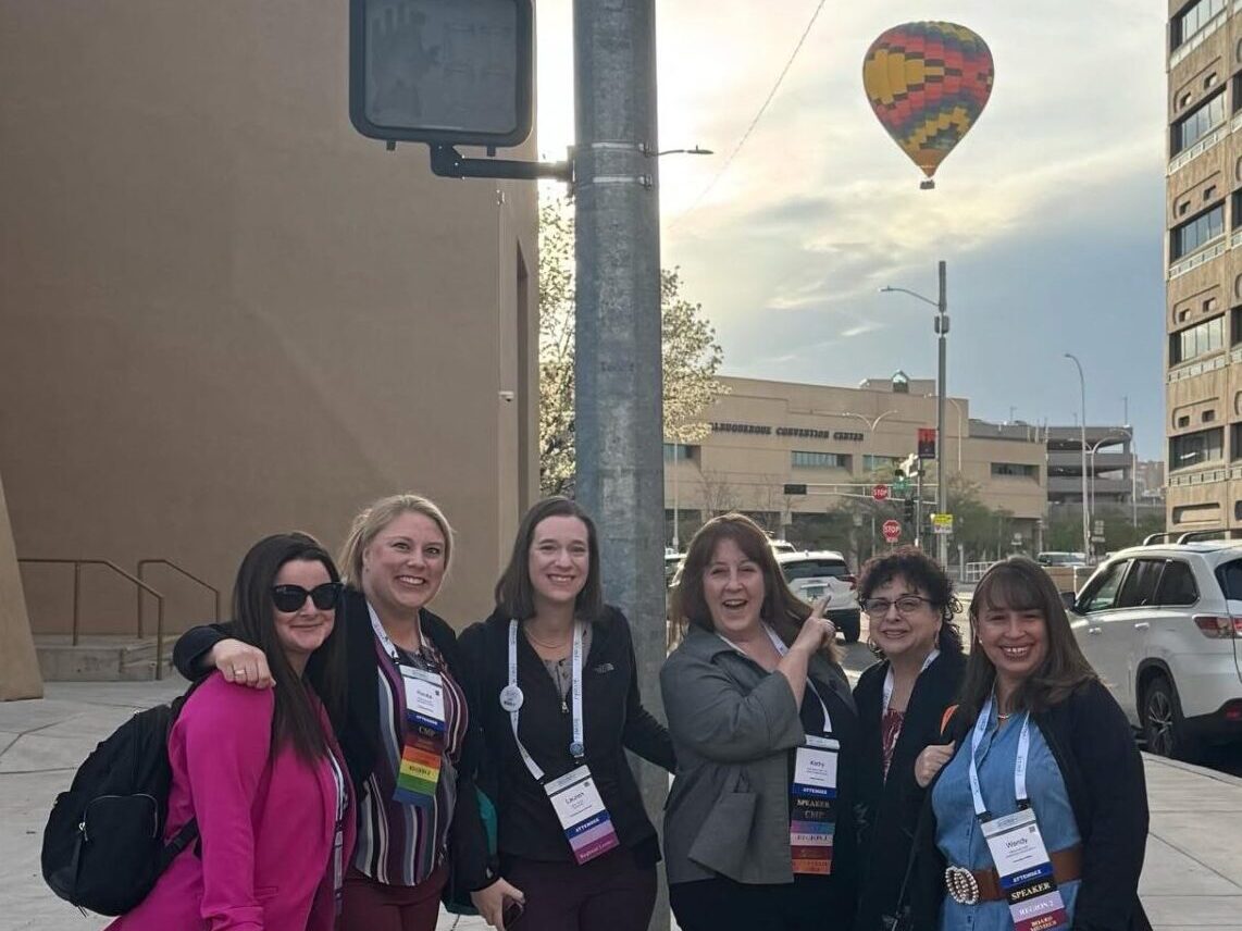 Kathy Walters pointing at a hot air balloon siting from the ACCED-I’s Annual Conference this past March in Albuquerque, New Mexico with other attendees and board members.