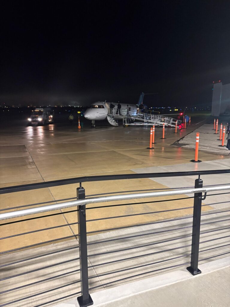 The view of a jet outside the Purdue University Airport Terminal with passengers boarding in the evening